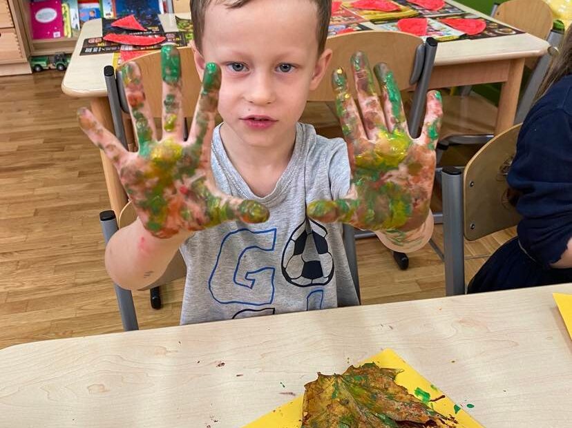 Chłopiec pokazuje dłonie zamoczone w farbie.