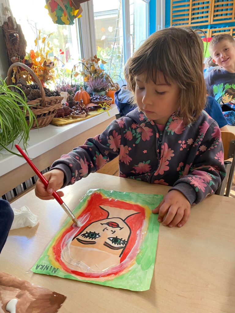 Dziewczynka maluje farbami wodnymi Panią Jesień.