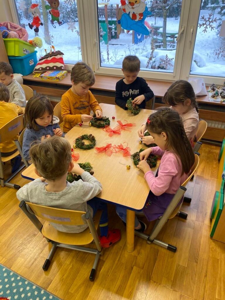 Dzieci z grupy "Słoneczka" wykonują świąteczne wianki podczas warsztatów.