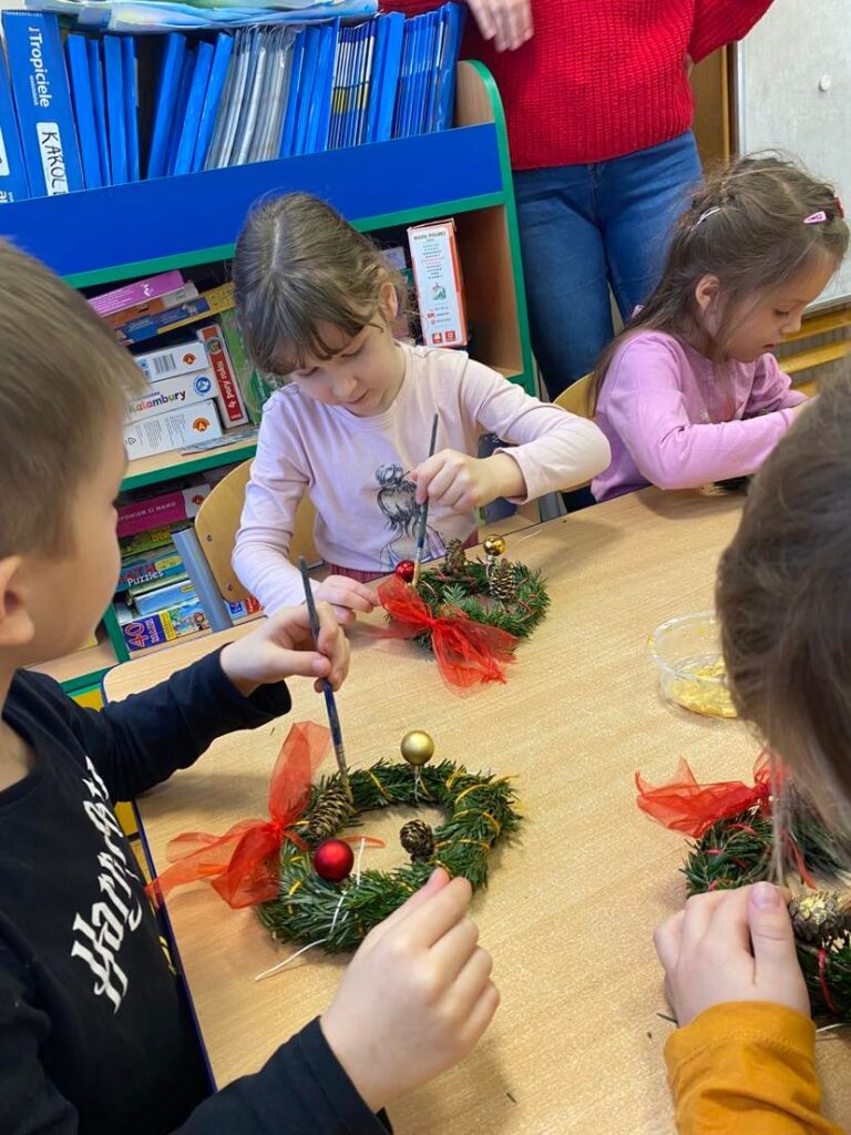 Dzieci z grupy "Słoneczka" wykonują świąteczne wianki podczas warsztatów.