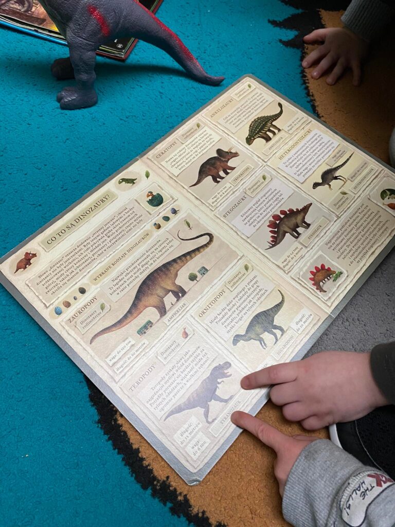 Dzieci oglądają książki o dinozaurach.