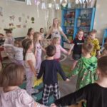 Dzieci ubrane w piżamy tańczą w przystrojonej sali.