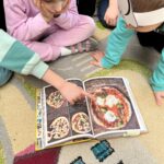 Dzieci oglądają książkę kucharską z przepisami na pizzę