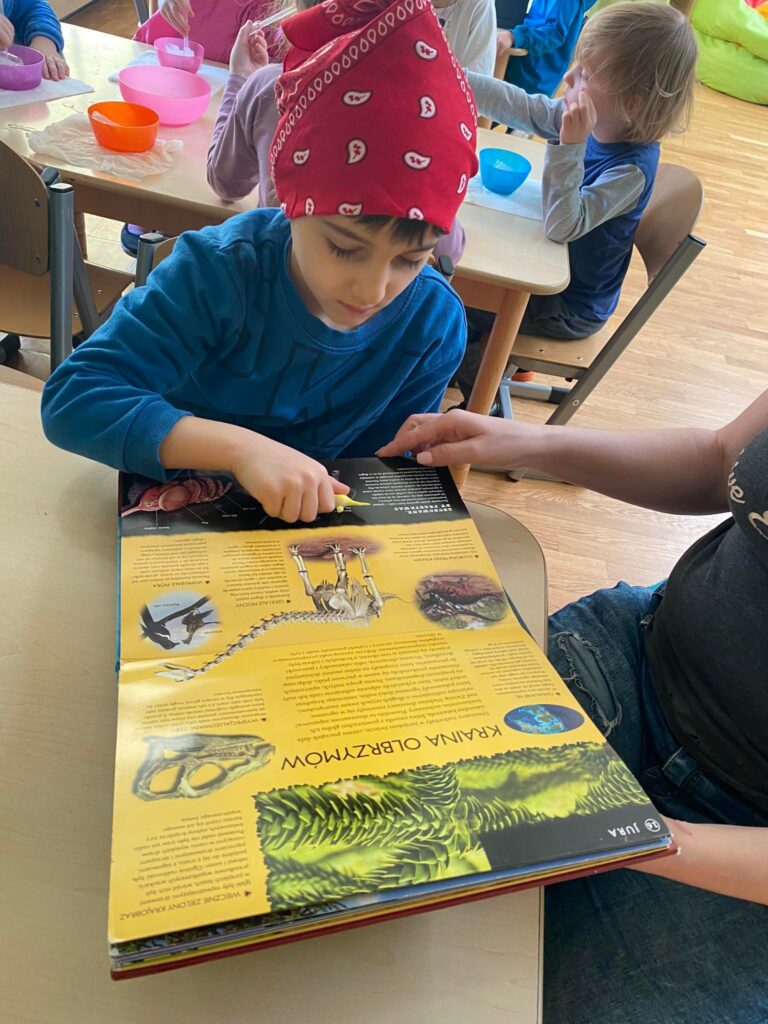 Dziecko ogląda książkę o dinozaurach.