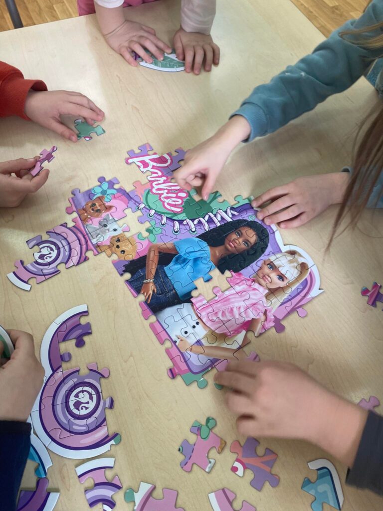 Dzieci układają puzzle Barbie.