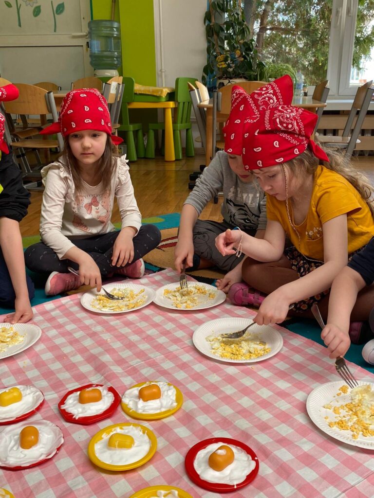 Dzieci siedząc na dywanie wykonują jajka z pianki do golenia.