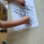 Dziecko maluje węglem za pomocą dwóch rąk
